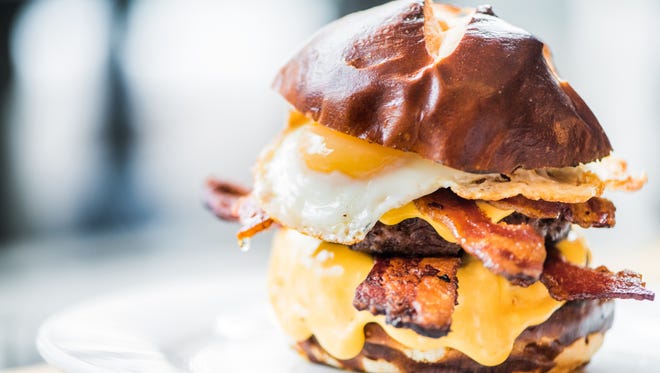 At Takoda in Washington, D.C., the Triple Bacon Burger boasts two bacon-infused patties, applewood smoked bacon, bacon and blue cheese fondue, and a sunny side up egg on a pretzel bun.
