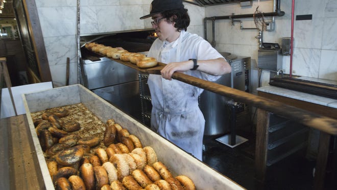 Baker Jefferson Arcila removes freshly baked bagels from the wood-burning oven at Black Seed Bagels in the East Village neighborhood of New York.