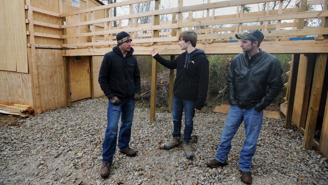 Jordan Kingery, left, Aaron Adams, center, and Bryan Riffle talk about putting the cabin together Saturday at Rising Son Church in Kingston. The cabin was completed with donations from Lowe's in memory of Marcus Weaver.