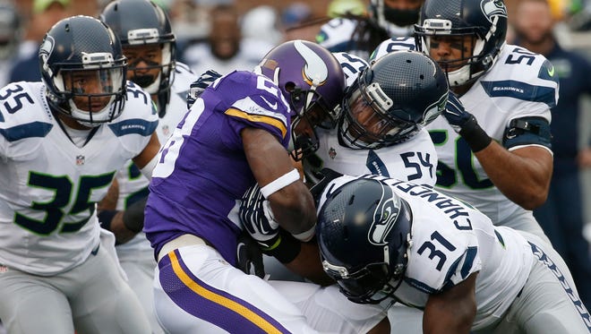 Minnesota Vikings running back Adrian Peterson (28) is stopped by Seattle Seahawks defenders including  linebacker Bobby Wagner (54) and strong safety Kam Chancellor (31)in the first half of an NFL football game in Minneapolis. The Cardinals play the battered Minnesota Vikings on Thursday in Arizona.