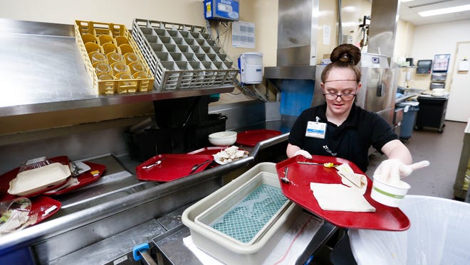 Twenty-four-year-old Tabby Hedgcorth clears trays in the kitchen at Cox Medical Center South on Thursday, Dec. 7, 2017. Hedgcorth has Down syndrome and was hired by CoxHealth after working there through the Developmental Center of the Ozarks' employment services program.