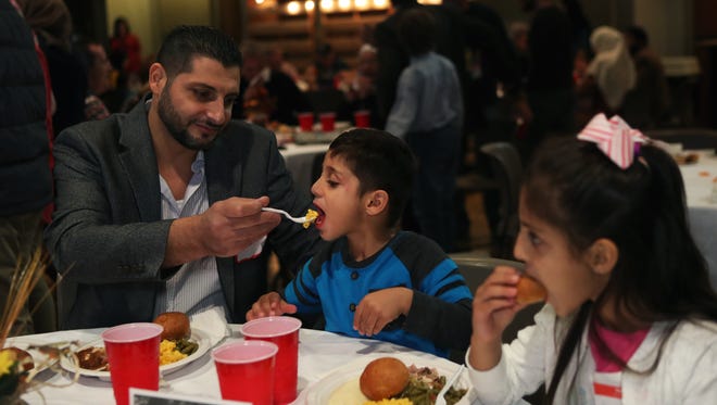 Mahmood Anhazaz, 38, feeds his 4-year-old son, Anas, macaroni and cheese during the annual Heartsong Church and Memphis Islamic Center Thanksgiving dinner at Heartsong Church in Cordova on Nov. 16, 2017. Anhazaz, his wife and four children are Syrians who arrived to Memphis two years ago from a refugee camp in Jordan.