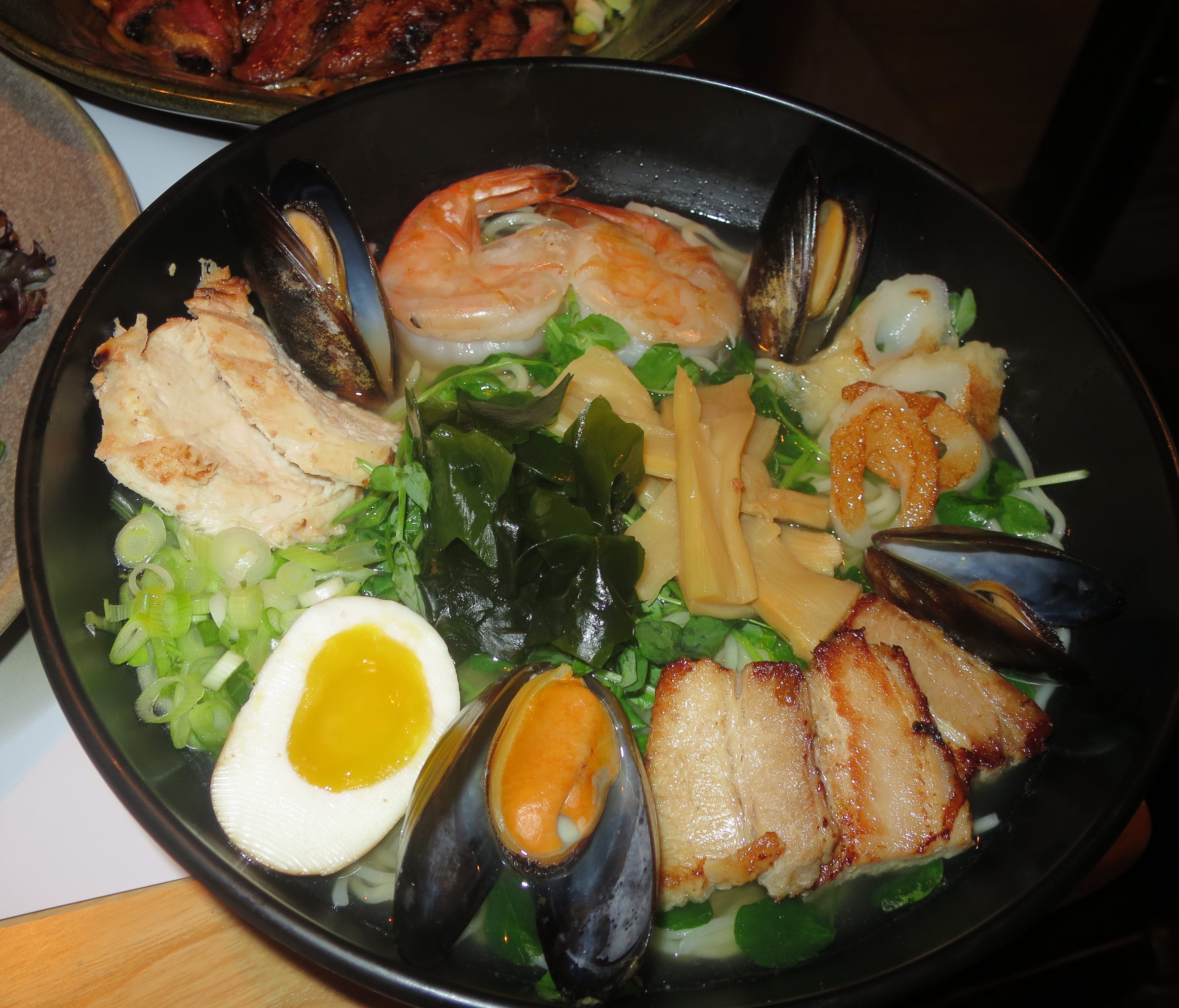 Ramen dishes are the bestsellers in the USA, and this is the namesake Wagamama ramen, with a little bit of everything: chicken, mussels, shell on shrimp, Japanese fish cake, pork belly, ramen noodles, scallions, pea shoots, seaweed, bamboo shoots and
