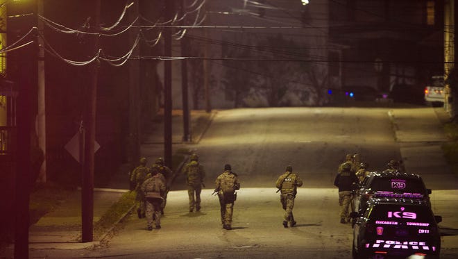 A SWAT team walks along a street in the neighborhood where a police officer was fatally shot Friday, Nov. 17, 2017, in New Kensington, Pa. Authorities in Pennsylvania say a police officer was shot and killed while making a traffic stop and a search is underway for the gunman. (Rebecca Droke/Pittsburgh Post-Gazette via AP)