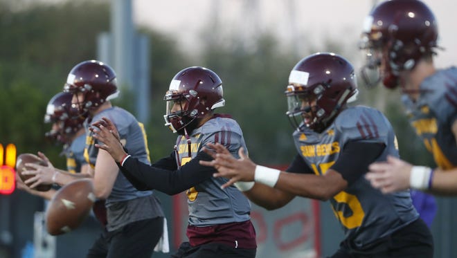 ASU's Manny Wilkins (5)(center) and other quarterbacks take snaps while warming up during a spring practice at Kajikawa practice fields on March 16, 2018 in Tempe, Ariz.
