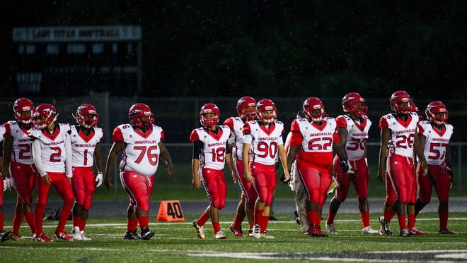 Immokalee High School football players walk on the field during a game against Golden Gate on Friday, Aug. 26, 2016.