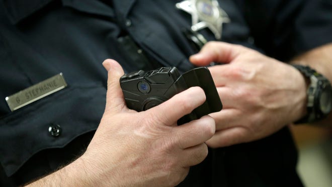 A police officer puts on a body-worn camera. The Clarksville Police Department may start using them next year.