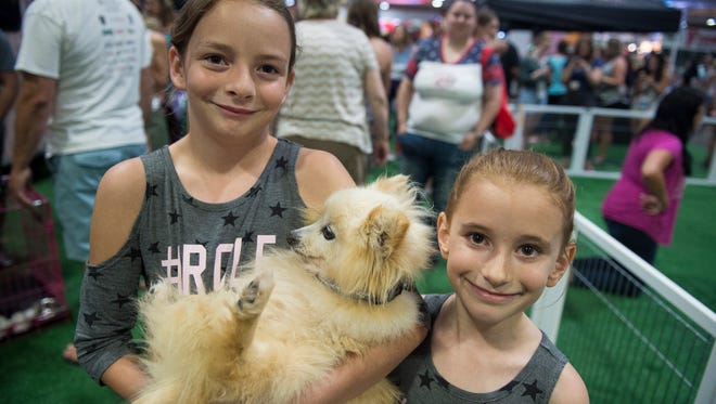 Ella Clark, 9, and her sister Memphis Clark, 8, who live in Thompson's Station, pose for a photo with their new dog, Pistol Andy, at the MuttNation Foundation's area of Fan Fair X at Music City Center on Thursday, June 7, 2018, in Nashville.
