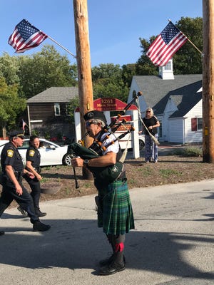 Playing Amazing Grace on bagpipes, Dave Knauer leads the village's 2019 procession from the fire station to St. Mary's.