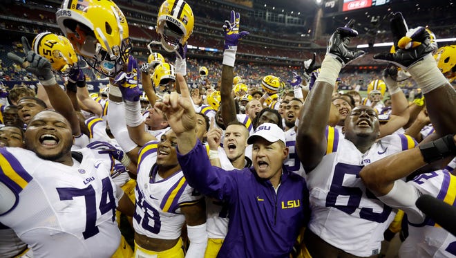 LSU coach Les Miles, center, is surrounded by his team as they celebrate beating Wisconsin in an NCAA college football game Saturday, Aug. 30, 2014, in Houston. LSU won 28-24.