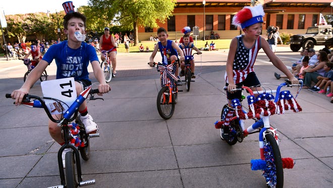 Young bicyclists patriotically pedal through downtown Abilene during the city's first community-wide Independence Day parade on Tuesday. Large crowds lined Cypress Street from North First Street to the Abilene Convention Center to watch the procession.
