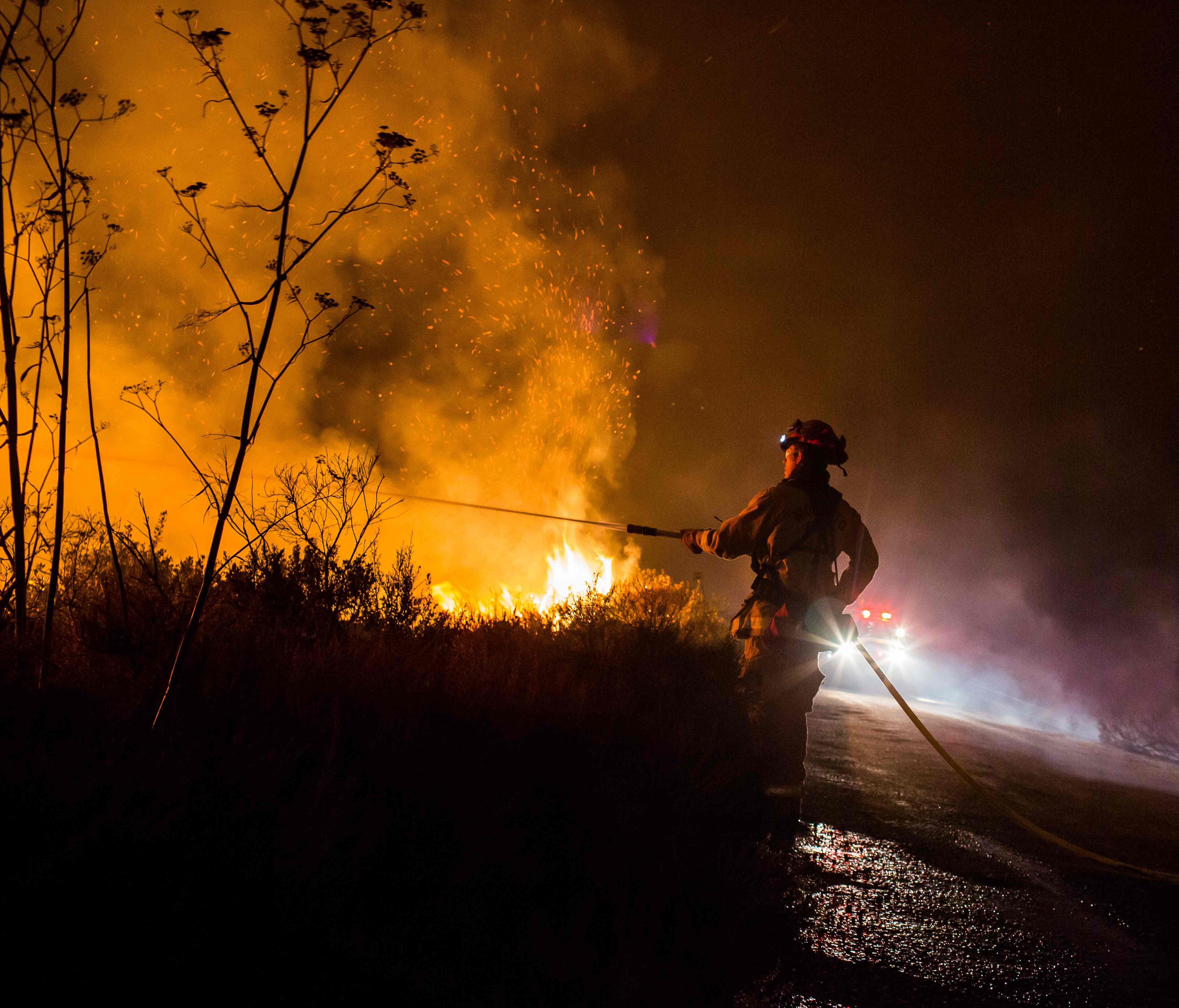 Firefighters work to extinguish the Thomas Fire as it burns past the 101 Highway towards the Pacific Coast Highway in Ventura, California, December 7, 2017.