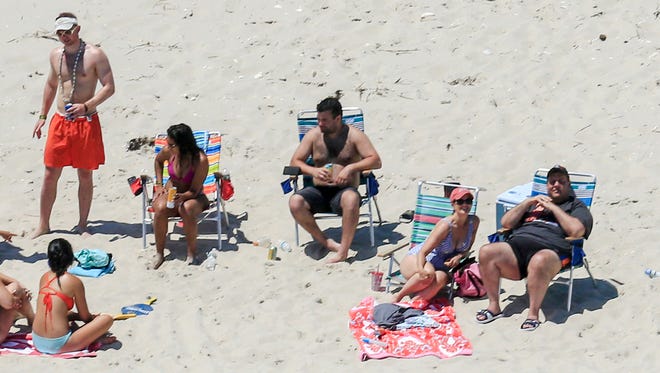 In this Sunday, July 2, 2017, photo, New Jersey Gov. Chris Christie, right, uses the beach with his family and friends at the governor's summer house at Island Beach State Park in New Jersey.