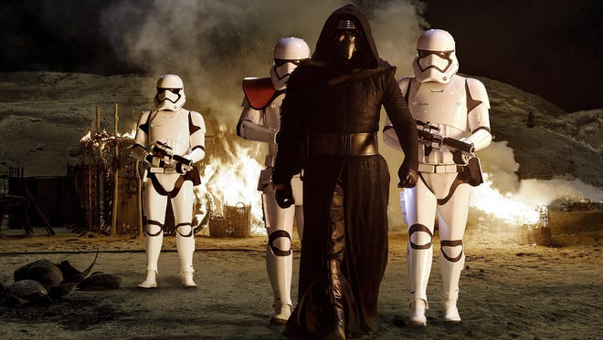 Kylo Ren (played by Adam Driver, center) with Stormtroopers in a scene from “Star Wars: The Force Awakens.”