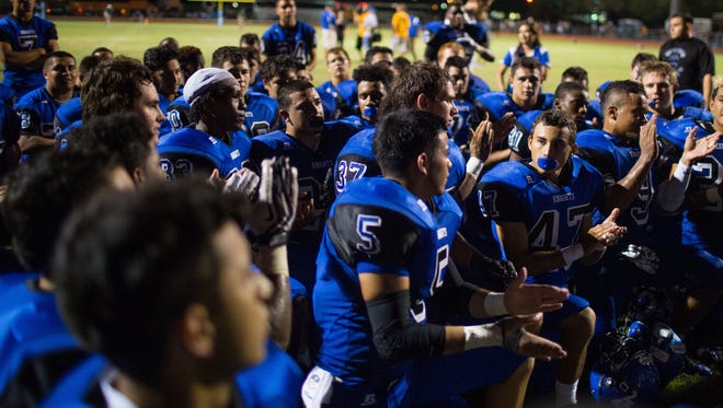 The Westview high school football team takes a knee to listen to coaches after its win over Basha on Sept. 25, 2014, in Avondale.
