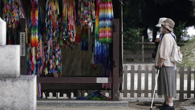 Visitors watch strings of paper cranes dedicated to the victims of the 1945 atomic bombing, at Hiroshima Peace Memorial Museum in Hiroshima, western Japan, Tuesday, Aug. 4, 2020. Survivors of the U.S atomic bombing share a growing sense of urgency as Hiroshima marks its 75th anniversary on Thursday, Aug. 6, 2020.