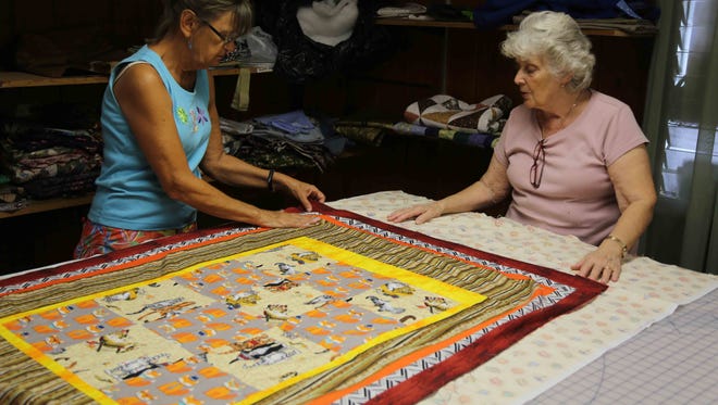 Mary Ann Sinagra and June Leighliter lay out fabric for a quilt.