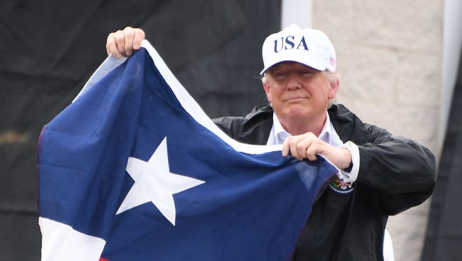 President Trump holds the state flag of Texas outside of the Annaville Fire House after attending a briefing on Hurricane Harvey in Corpus Christi, Texas, on Aug. 29, 2017.