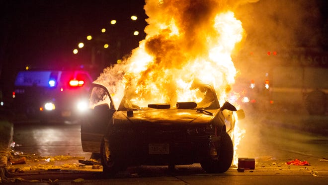 A car burns as a crowd of more than 100 people gathers following the fatal shooting of a man in Milwaukee, Saturday, Aug. 13, 2016. The Milwaukee Journal Sentinel reported that officers got in their cars to leave at one point, and some in the crowd started smashing a squad car's window, and another vehicle, pictured, was set on fire. The gathering occurred in the neighborhood where a Milwaukee officer shot and killed a man police say was armed hours earlier during a foot chase.