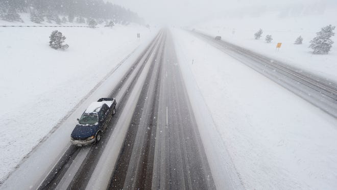 A lone pickup truck heads down the eastbound lanes of Interstate 70 as a severe spring storm packing high winds and heavy, wet snow sweeps over the intermountain West Saturday, April 16, 2016, near Evergreen, Colo.