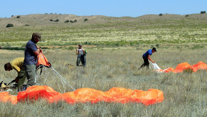 A team of smokejumpers with the U.S. Forest Service and the Bureau of Land Management gather their parachutes following a practice jump west of Albuquerque, N.M., on June 29, 2017. Federal agencies called for a boost in the number of resources in the Southwest due to the persistent fire danger, resulting in smokejumpers from Idaho and Montana being assigned to the region. (AP Photo/Susan Montoya Bryan)
