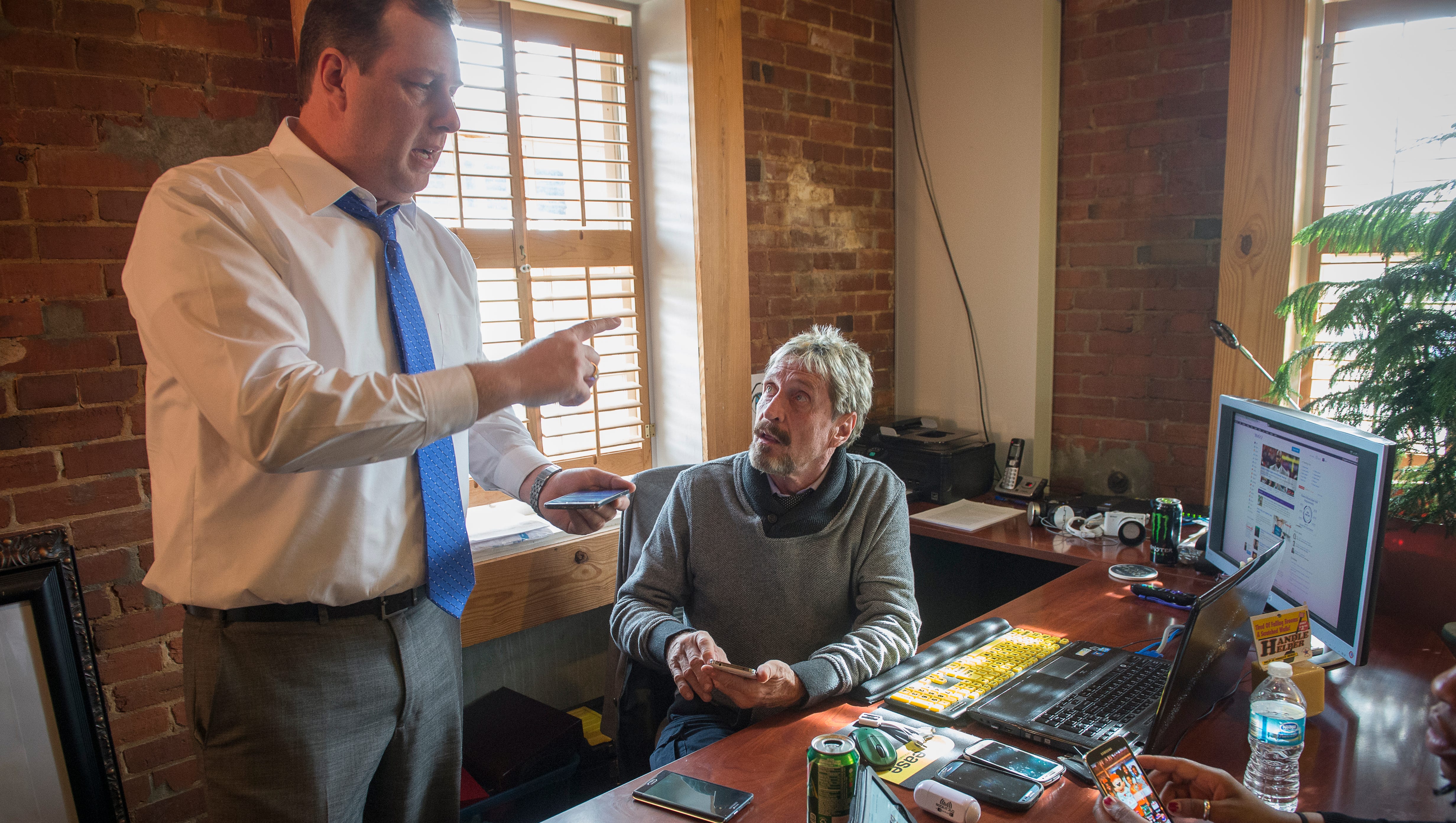John McAfee, center, speaks with business partner Tom Gusinski at The Round House in Opelika, Ala.