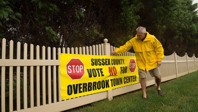 Rich Borrasso straightens a sign that advocates voting ‘No’ for the Overbrook Town Center, which would be across from the Red Fox Fun development in Milton.