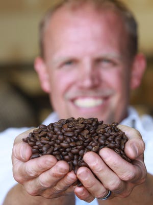 Jimmy's Java President Ric Kerns displays a mound of freshly roasted coffee beans; the company has been expanding.