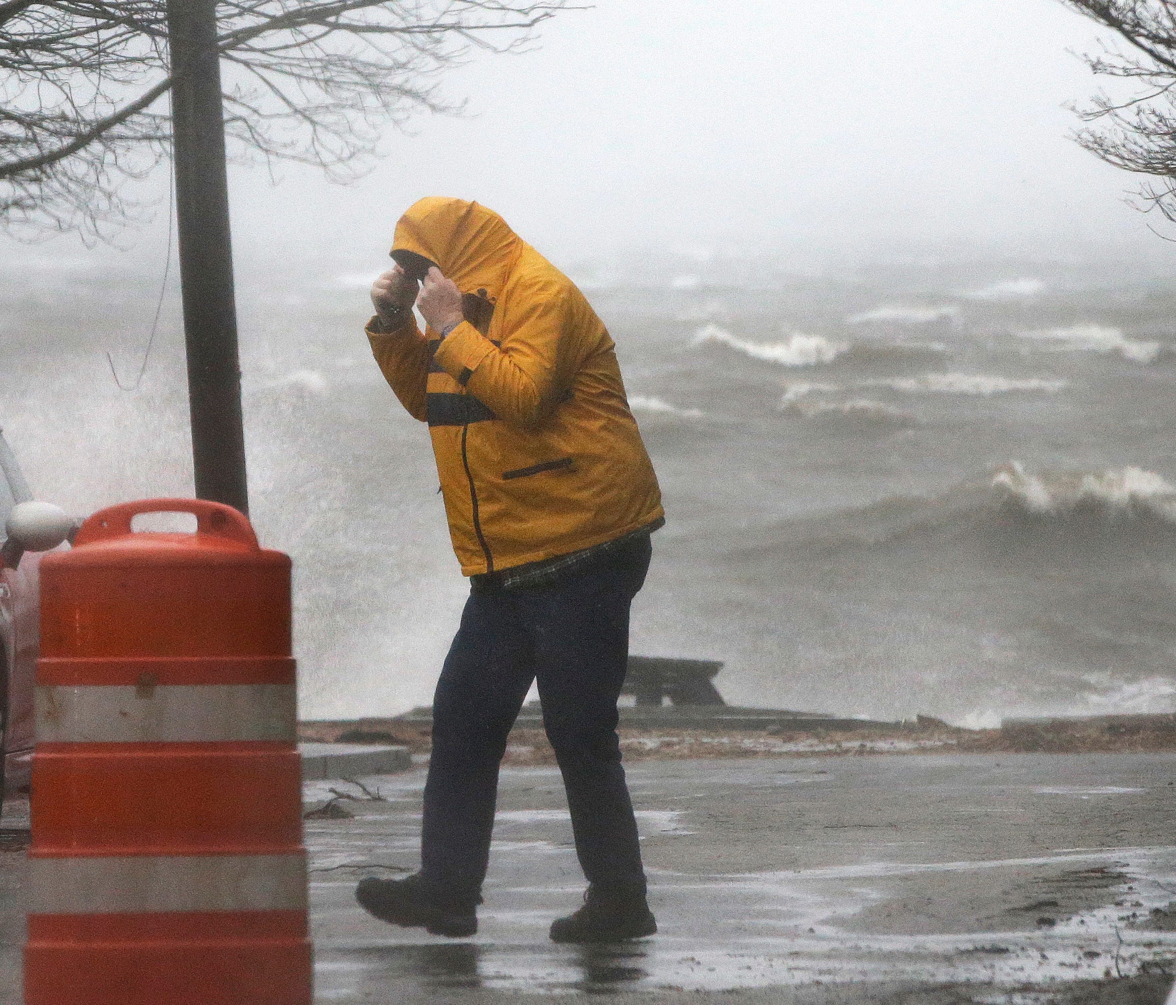 A pedestrian walks near the coastline in Newburyport, Mass. as a major nor'easter pounds the East Coast, packing heavy rain, intermittent snow and strong winds.