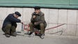 Two elderly men crouch on a smoke break in Pyongyang,