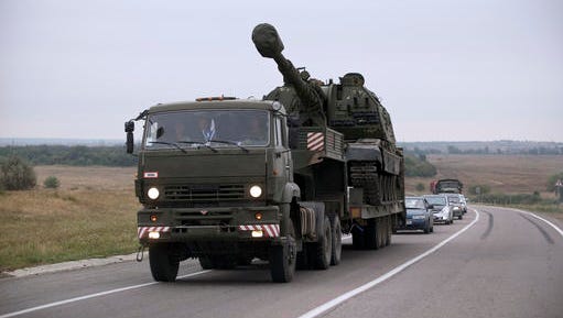FILE - In this Tuesday, Aug. 19, 2014 file picture, a Russian military truck carries a MSTA-S self-propelled howitzer about 10 kilometers from the Russia-Ukrainian border control point at town Donetsk, Rostov-on-Don region, Russia. Russian howitzers and rocket launchers regularly pounded Ukrainian positions across the border in the early stages of the war in eastern Ukraine, according to an analysis of hundreds of attack sites published by open source investigative group Bellingcat.