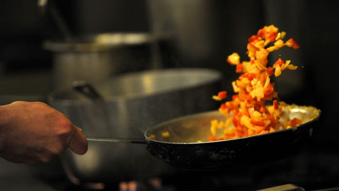 A Sonny Lubick Steakhouse chef tosses red pepper and onion over the stove on Monday, Feb. 25, 2013, in the restaurant's kitchen in Fort Collins.