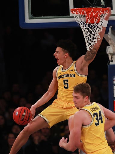 Michigan's D.J. Wilson reacts after a dunk against