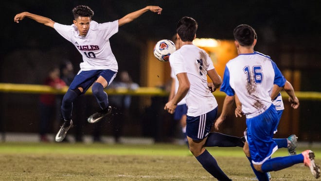 St. Lucie West Centennial's Zavier Sanchez (left) leaps in the air to stop the ball against Sebastian River during the first half of the high school boys soccer game Monday, Dec. 4, 2017, at South County Stadium in Port St. Lucie.