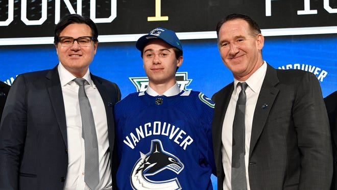 Quinn Hughes poses for a photo with team representatives after being selected as the No. 7 overall pick by the Vancouver Canucks in the first round of the 2018 NHL draft at American Airlines Center in Dallas on June 22.