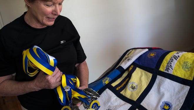 Runner Nona Cerveny of Scottsdale shows off her first 29 Boston Marathon finisher medals and a quilt made from her first 25 souvenir shirts from the race. She completed her 30th Boston Marathon in a row Monday, April 20,  240 days after surgery to remove a golf-ball-sized tumor from her brain and less than two months after completing chemotherapy treatments.