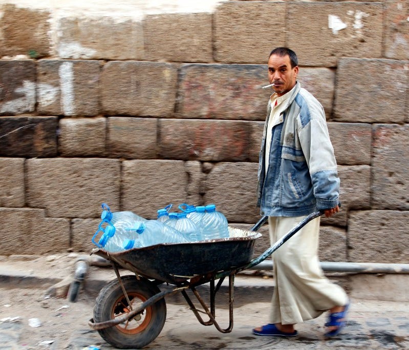 A Yemeni pushes a wheelbarrow with donated bottles of water, Sana, Feb. 10, 2017.