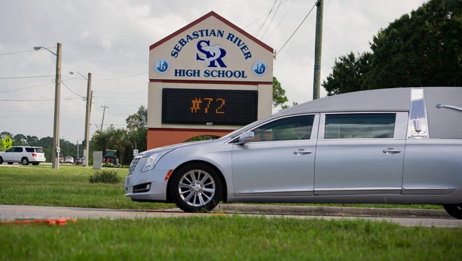 A hearse for fallen football player William Shogran Jr. drives past a sign showing his number after his funeral service at the Sebastian River High School Performing Arts Center on Tuesday, Aug. 19, 2014. The 14-year-old boy, the son of Florida Highway Patrol Trooper William Shogran, died Aug. 13 while away at a training camp with the school's team.