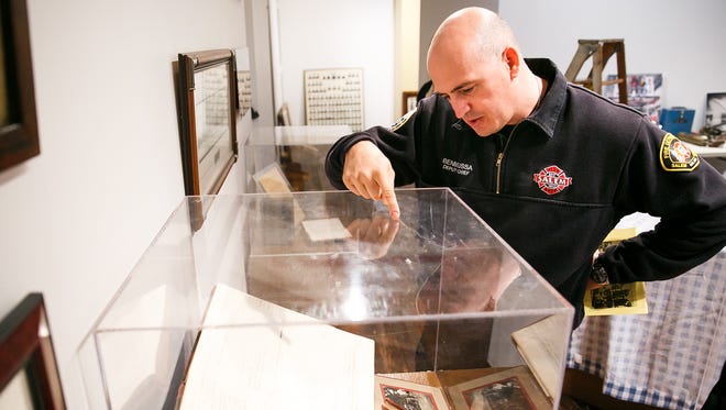 Salem Deputy Fire Chief Gabriel Benmoussa points out items on a ledger from the early 1900s at the Willamette Heritage Center's Salem Fire Department exhibit on Monday, Oct. 23, 2017. The exhibit opened Nov. 7 and will run through Dec. 23.