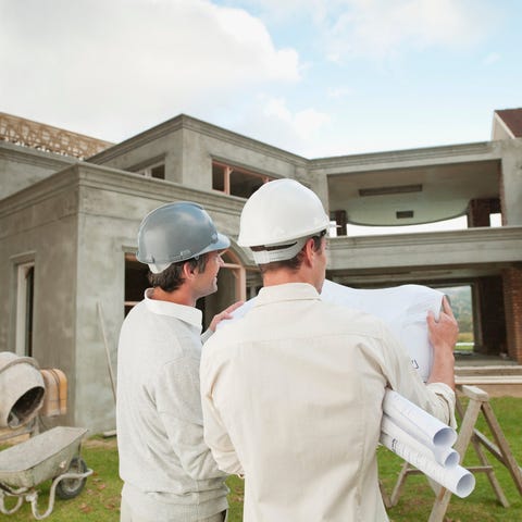 Homebuilders review a blueprint in front of house 