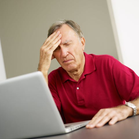 Older man at laptop with distressed expression hol