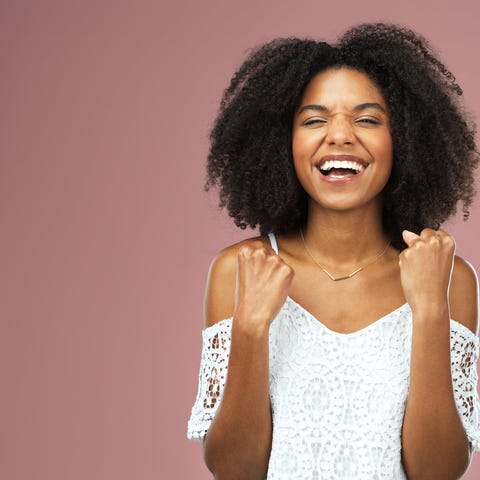 A young woman cheering against a pink background.