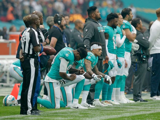 Miami Dolphins players kneel down during the national