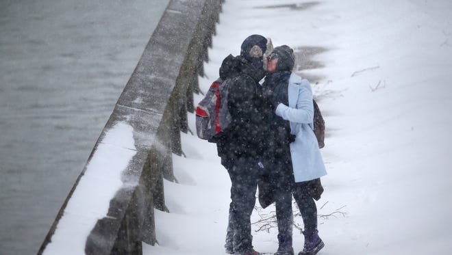 Will Costello and Paula Simpson steal a kiss while making their way home along the river walk from the Rochester Central Library during the beginning of a snowstorm.