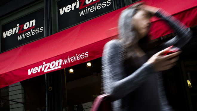 A pedestrian uses her cellphone as she passes a Verizon Wireless store on Broadway in Lower Manhattan in  2013.