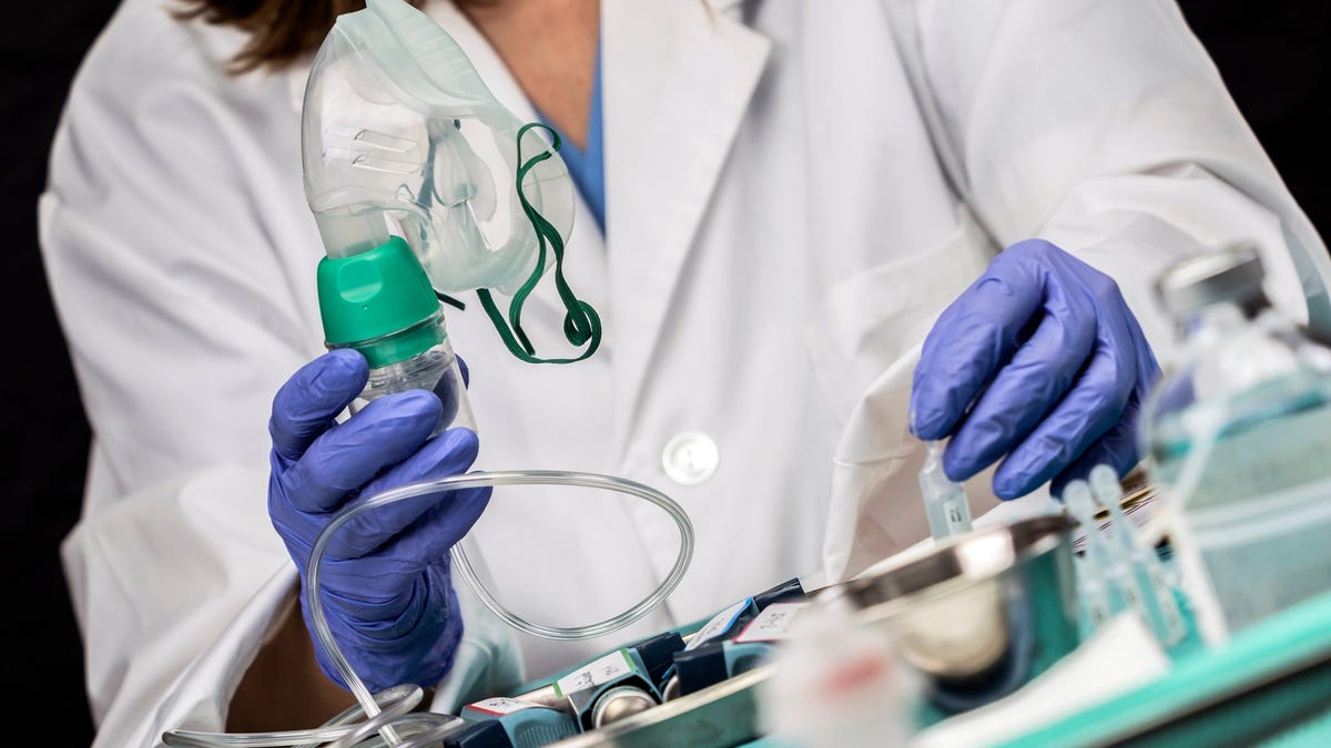 Doctor with protective gloves holding ventilator mask