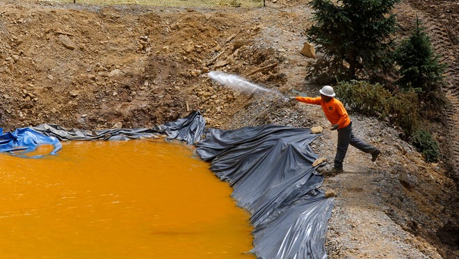 A Environmental Restoration, LLC employee treats water in a to a temporary holding facility, Monday, Aug. 10, 2015, at the Gold King Mine site north of Silverton, Colo.