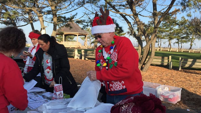 Mark Speaker, member of the Lavallette Business Association, helps a runner register for the Ugly Lavallette Christmas Sweater Run on Dec. 5.