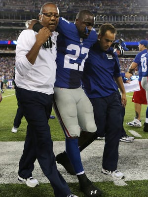 New York Giants strong safety Stevie Brown (27) is helped off the field after suffering a torn ACL in his left knee against the New York Jets at MetLife Stadium on Aug. 24, 2013.