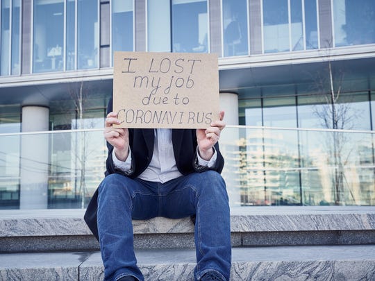 Man holding sign over his face stating he lost job due to coronavirus.